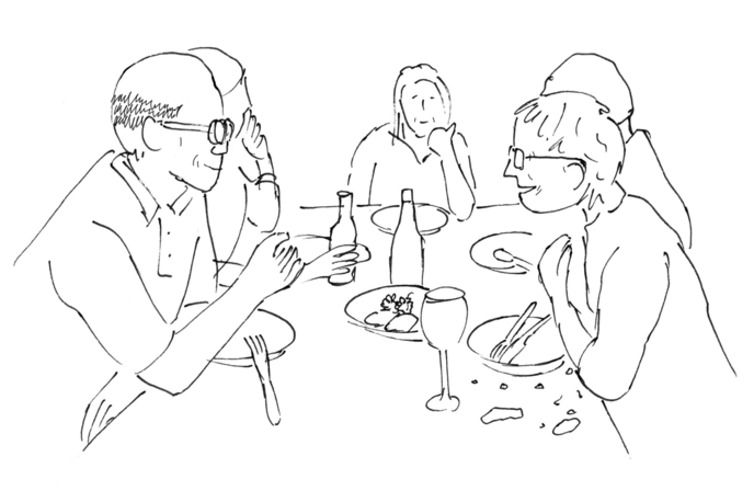 Personen sitzen am Tisch und essen gemeinsam