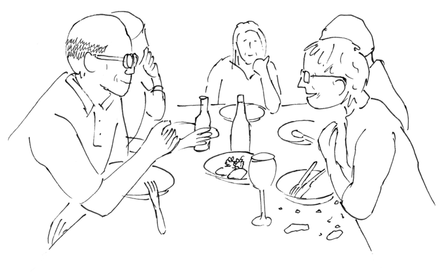 Personen sitzen am Tisch und essen gemeinsam