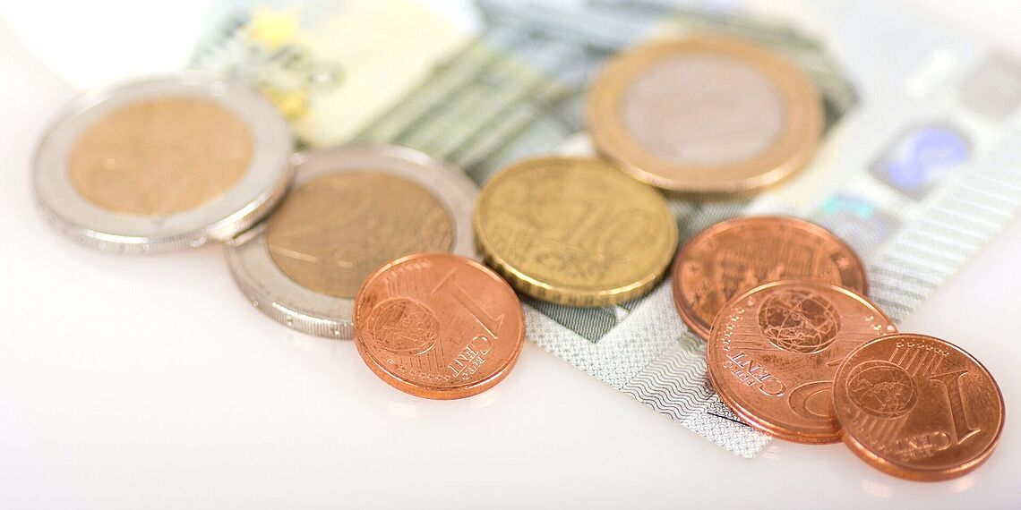 Münzen und Geldschein liegt auf Tisch